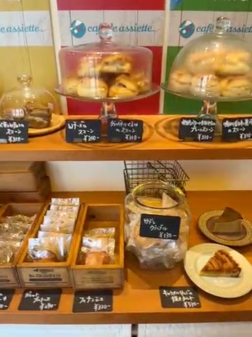 cafe de assietteの店内の棚。ガラスのふたの中のスコーンや、袋入りの焼き菓子、タルト(私が撮った動画から)