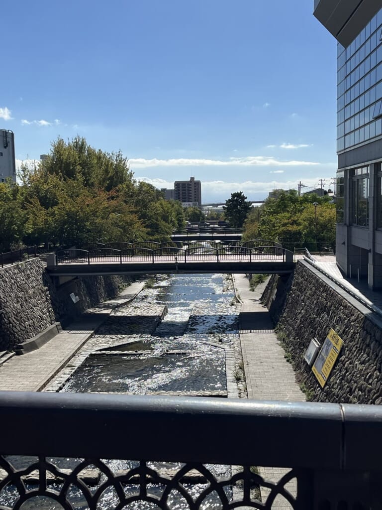 欄干ごしに見る都賀川。雨上がりの水面がキラキラ光る(私が撮影)