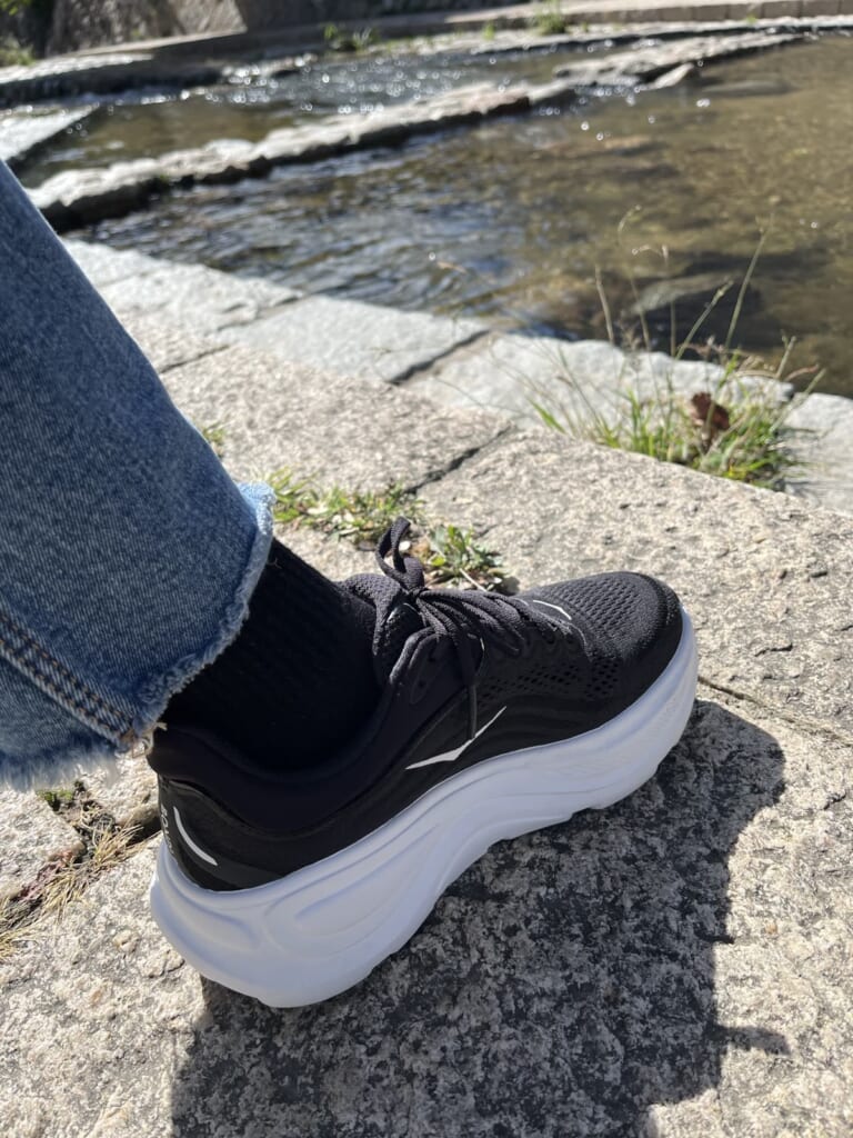 都賀川の遊歩道で、HOKA BONDI 9(黒)とデニムの足元(私が撮影)